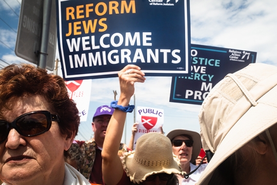 People at a rally holding up signs that say Reform Jews Welcome Immigrants