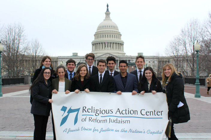 Group of teens standing in front of the US Capitol holding a Religious Action Center sign