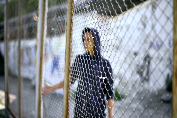 Blurry image of a teenage boy with his hand at a metal fence 