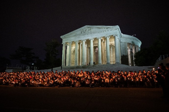 Photo of a group of teens sitting on capital hill holding candles